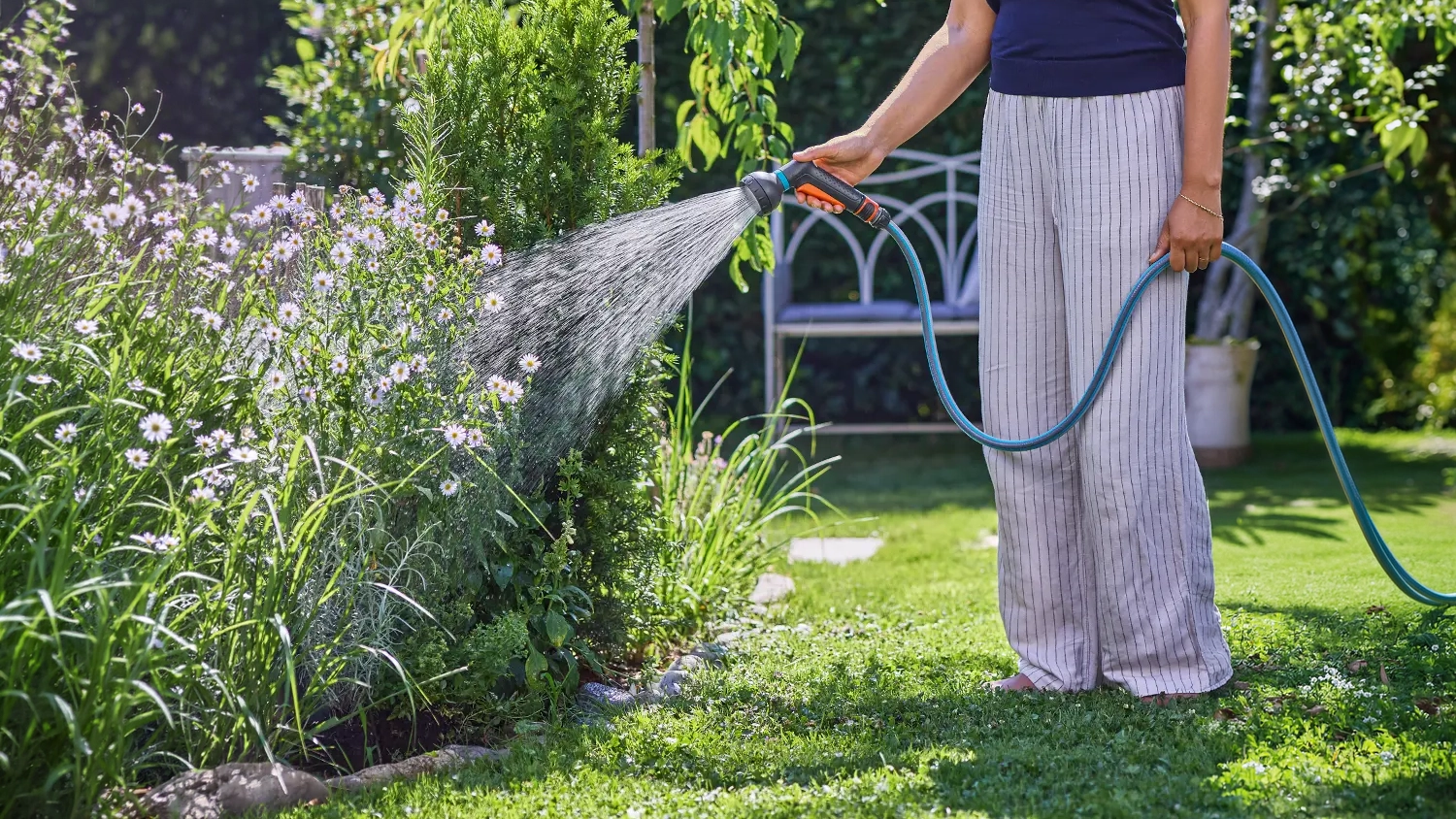 Žena zal&eacute;v&aacute; květiny pomoc&iacute; zavlažovac&iacute; sprchy GARDENA