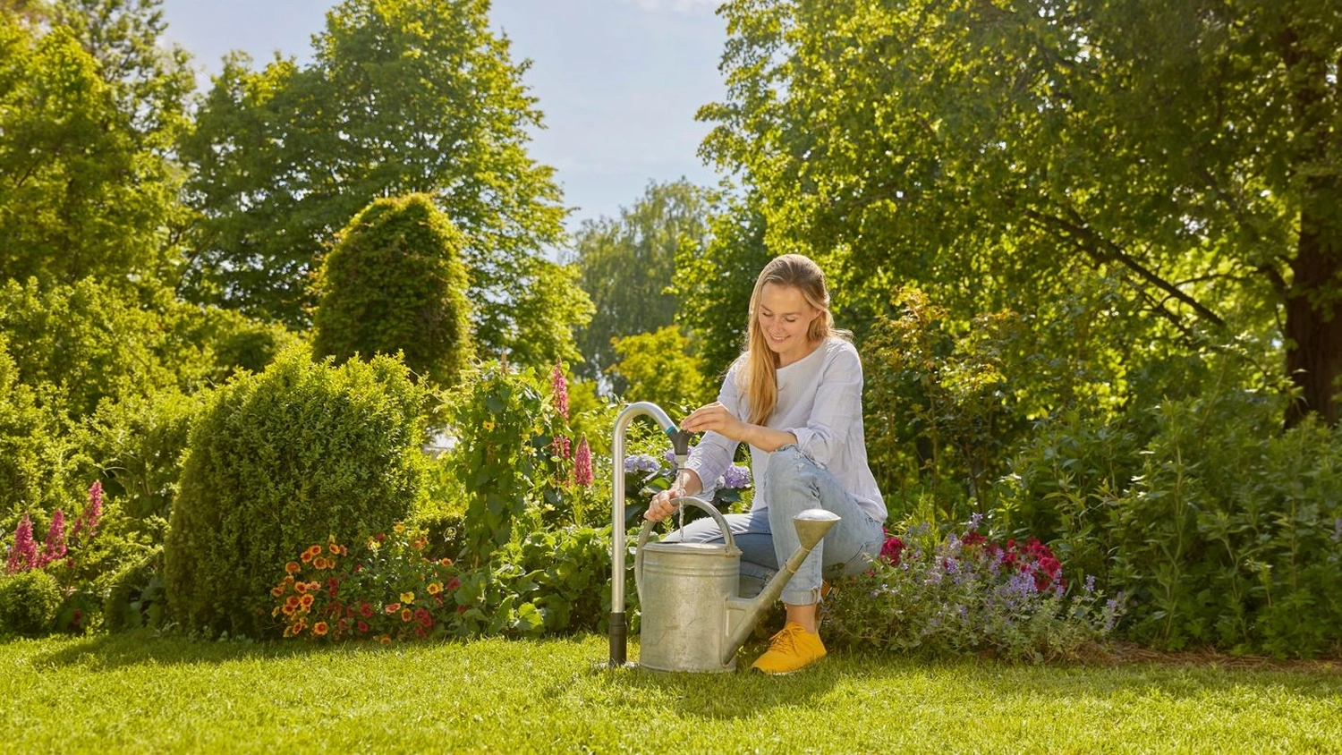 Žena pln&iacute; konev ze zahradn&iacute;ho vodovodn&iacute;ho kohoutku GARDENA