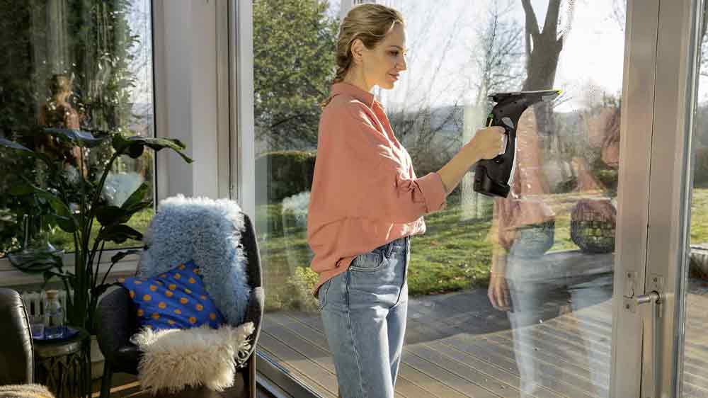 Žena čist&iacute;c&iacute; velk&eacute; prosklen&eacute; dveře na terasu vysavačem na okna K&auml;rcher WV 5 Plus Anniversary Edition_02
