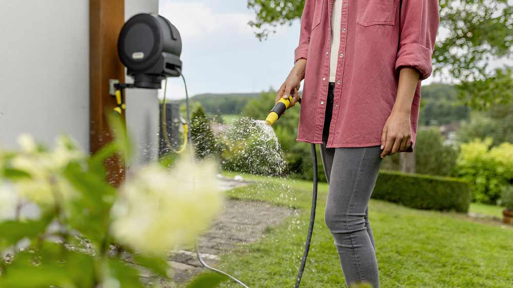 Žena zalévá zahradu s hadicí připojenou přes automatický naviják Kärcher HBX 4.20_03