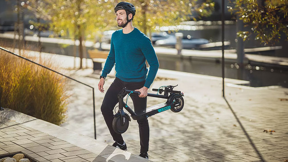 Muž nese složenou elektrickou koloběžku LAMAX E-scooter S7500 Plus_03