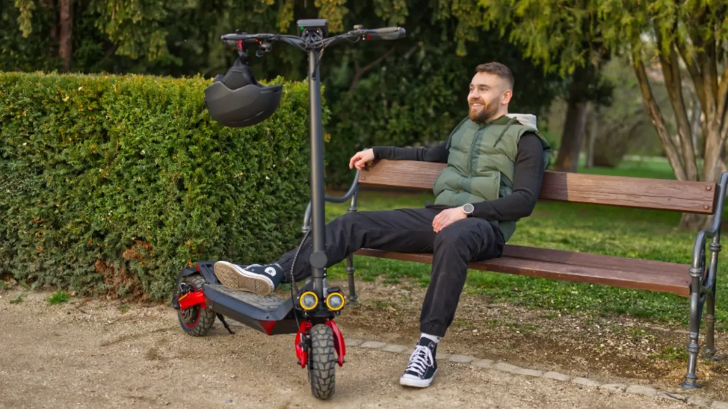 Muž sed&iacute; na lavičke s elektrickou kolobežkou Sencor