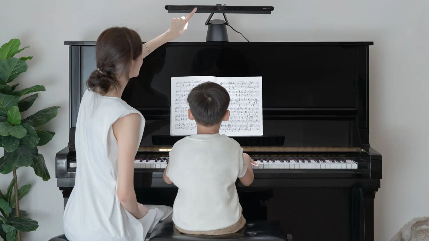 Žena nastavuje spr&aacute;vne osvetlenie klav&iacute;ra na lampe Benq PianoLight R Black