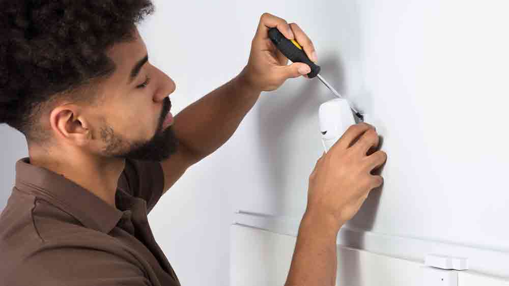 Muž připevňující detektor pohybu na zeď_03