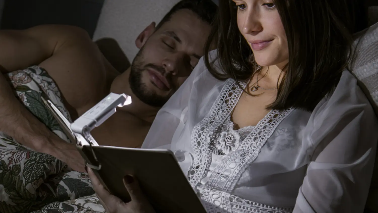 Žena čte v posteli knihu s LED lampičkou na čtení Retlux RTL 213