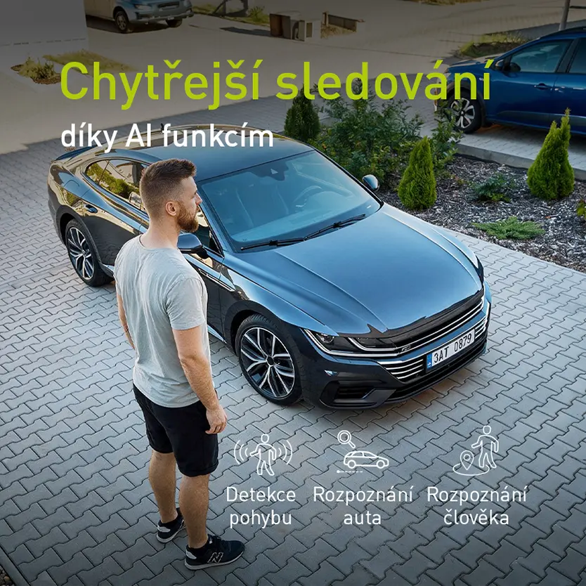 Muž stojící u zaparkovaného automobilu před domem