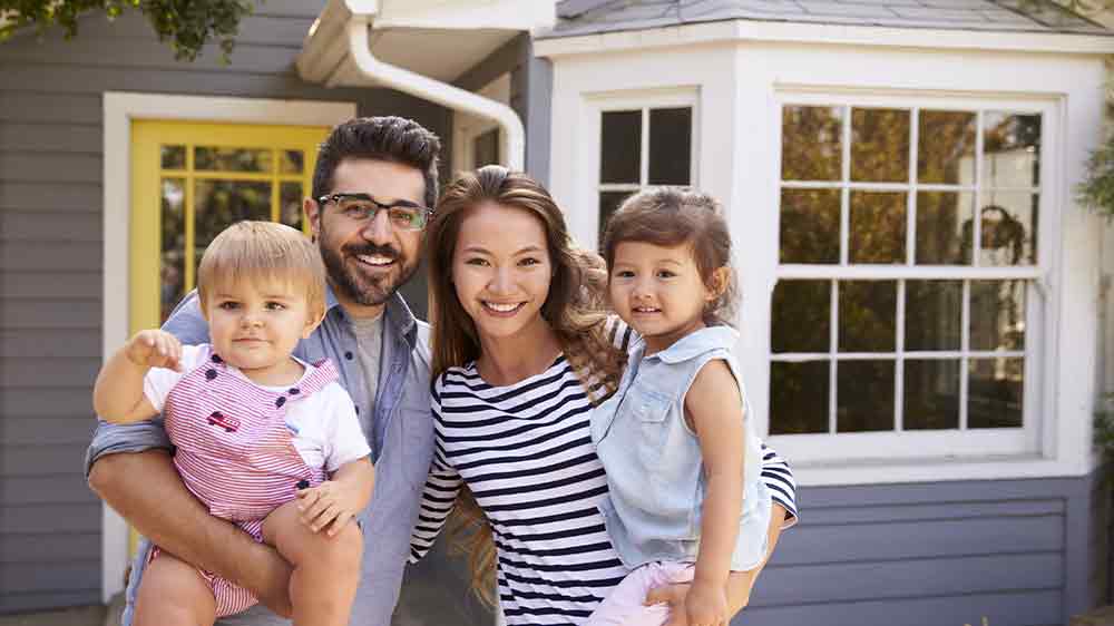 Usmievajúca sa mladá rodina pred domom_02