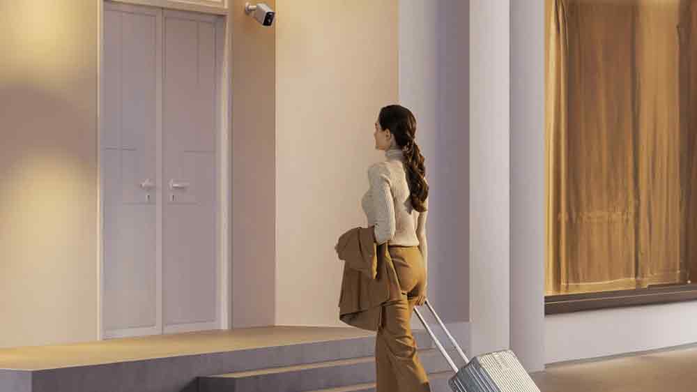 Žena s kufrom kráčajúca ku vchodovým dverám s inštalovanou vonkajšou kamerou Xiaomi_05