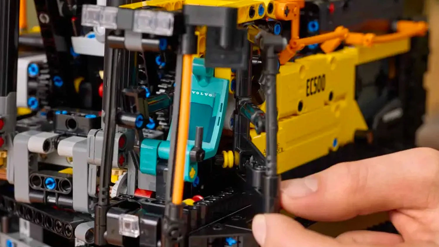 Muž otevírá dveře bagru ze stavebnice LEGO® Technic 42215 Bagr Volvo EC500 Hybrid.