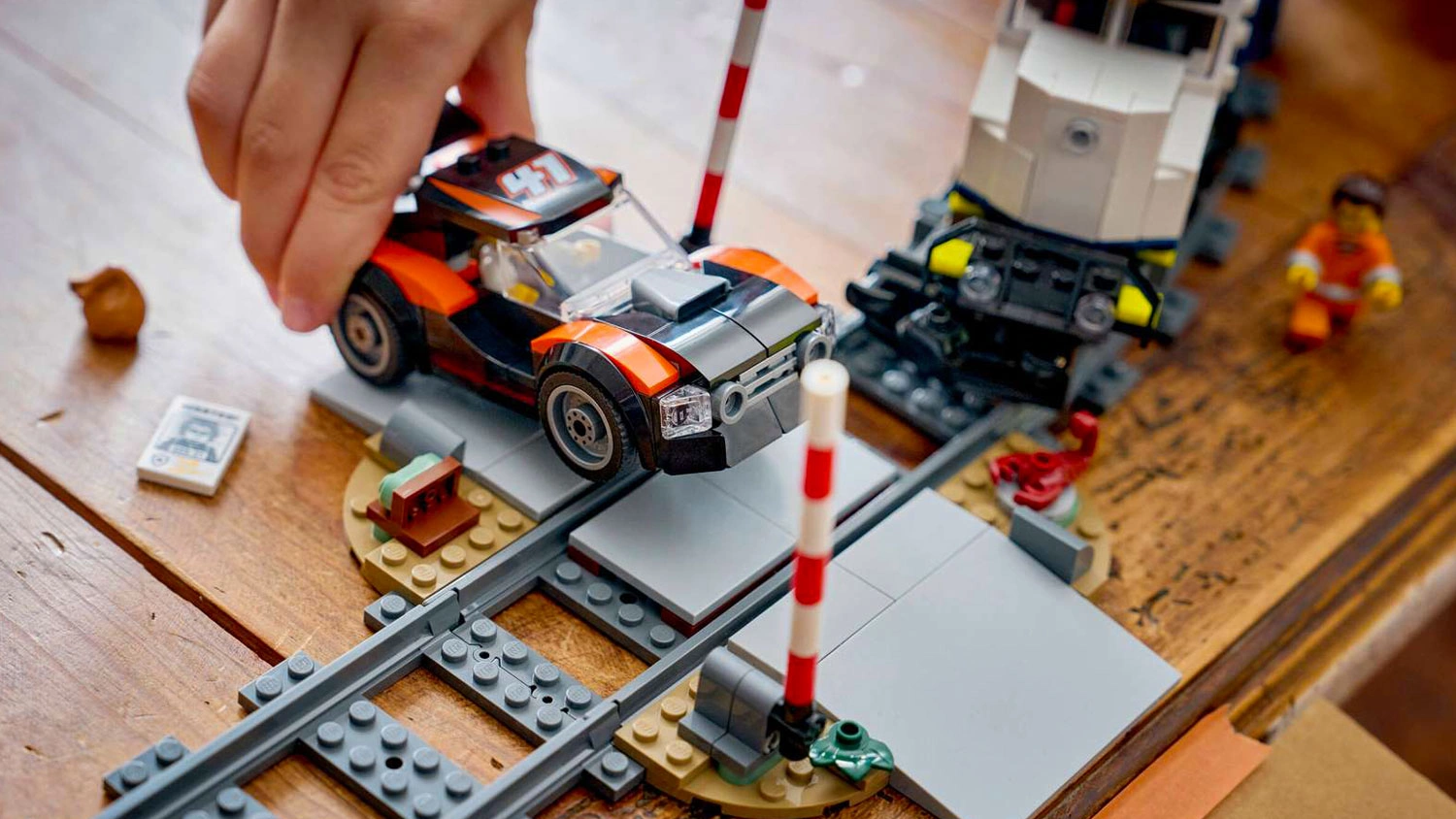 Ruka držící závodní auto přejíždějící přes koleje ze stavebnice LEGO® City 60508 Loupež v policejním vlaku