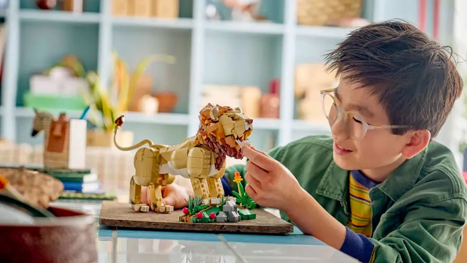 Chlapec si hr&aacute; s modelom leva LEGO&reg; Creator 3 v 1 31386 Divok&eacute; zvierat&aacute;: Majest&aacute;tny lev