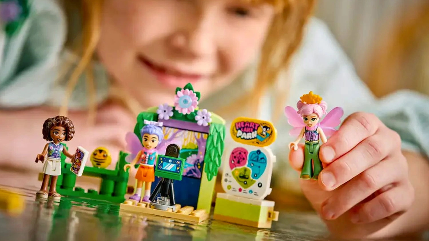 Holčička stav&iacute; kostky LEGO&reg; Friends 42702 Květinov&yacute; kolotoč s v&iacute;lami