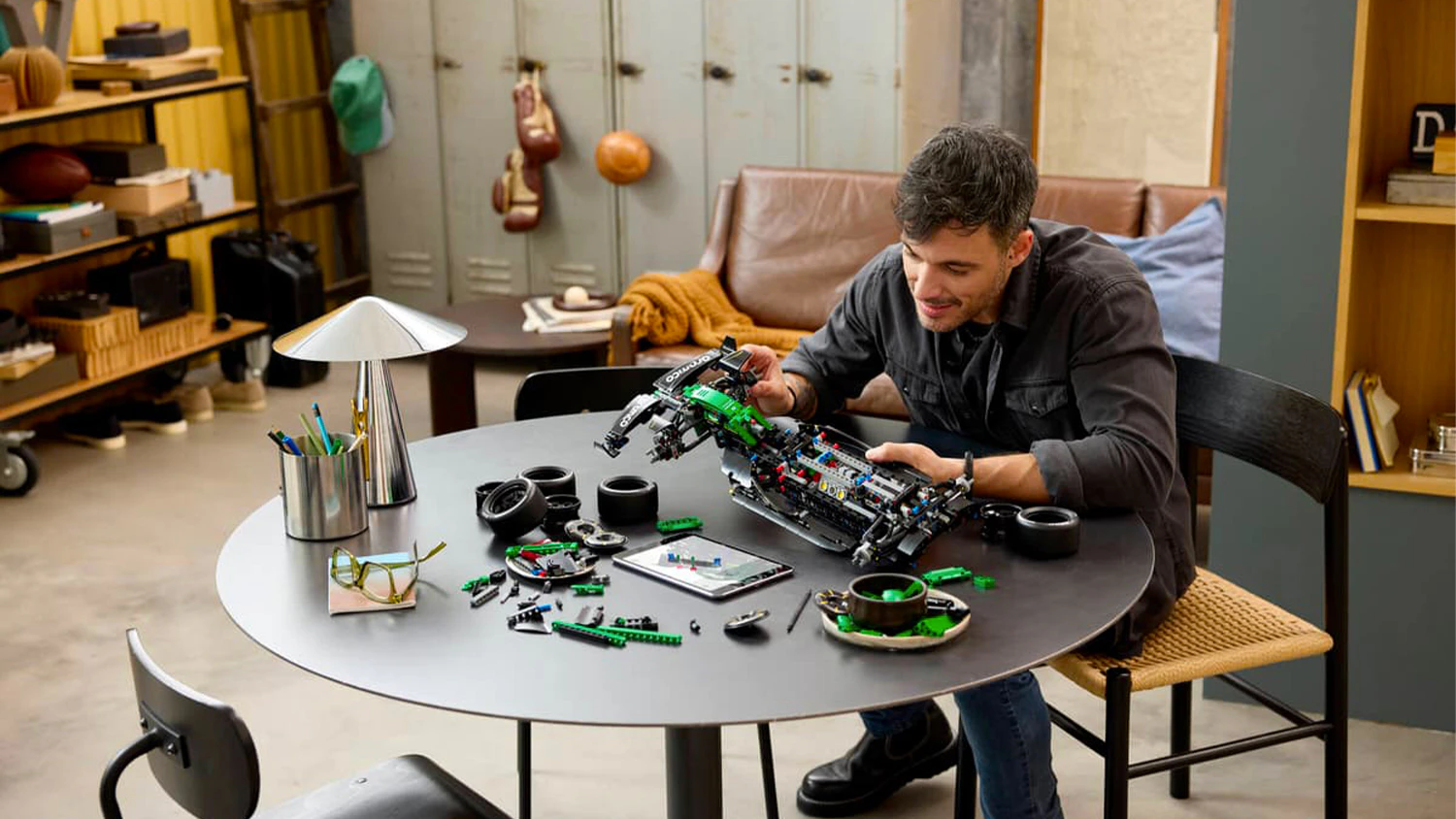 Muž u stolu stavějící LEGO® Aston Martin