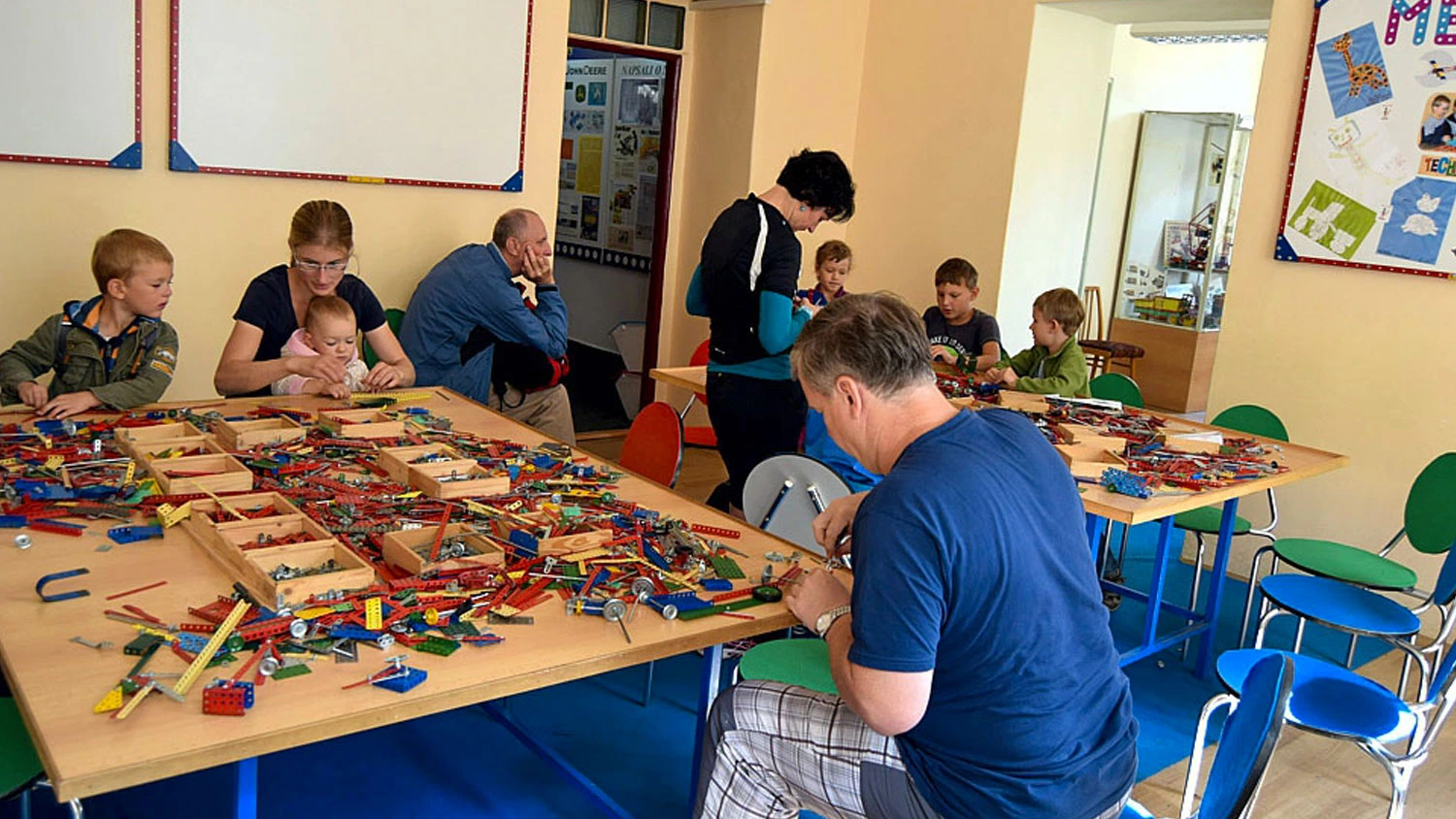 Lidé u stolu staví stavebnici Merkur