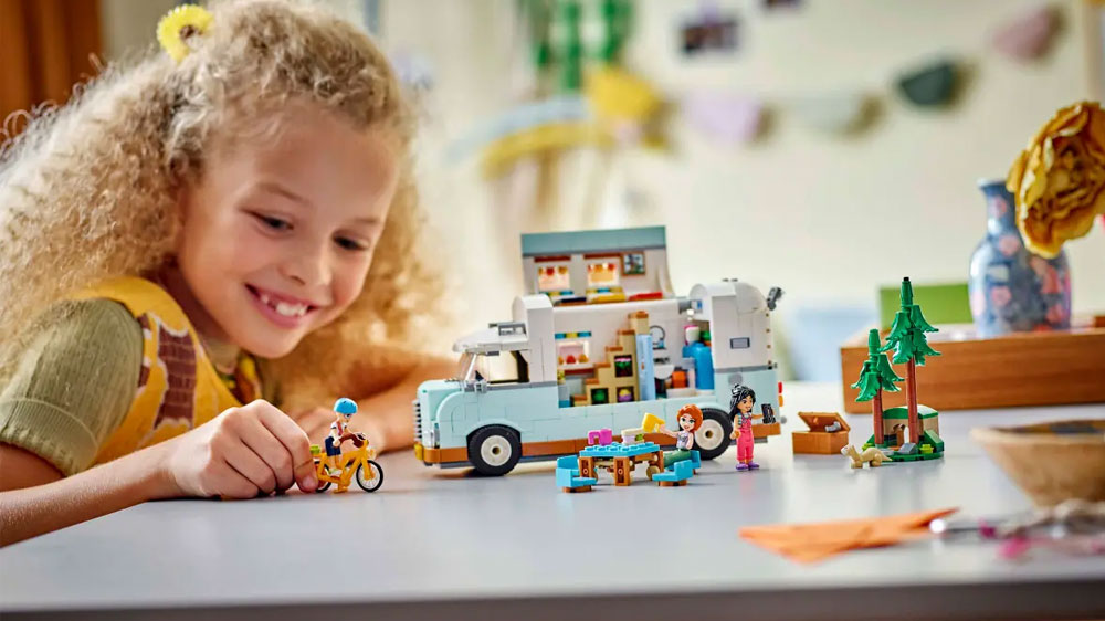 Holčička hrající si se stavebnicí LEGO® Friends 42633 Dobrodružství s karavanem přátelství u stolu _03