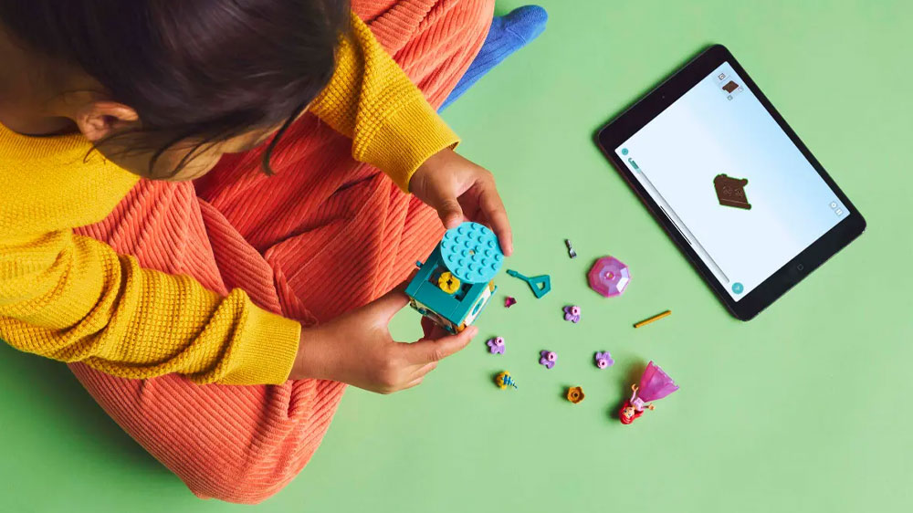 Holčička staví stavebnici LEGO® Dysney Princess 43259 Točící se Ariel za pomoci aplikace Lego Builder na zemi pohledem shora_02