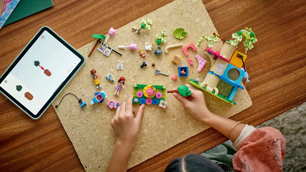 Dívka sestavuje stavebnici LEGO® Friends Kočičí narozeninová oslava a dům na stromě s pomocí aplikace v tabletu_04