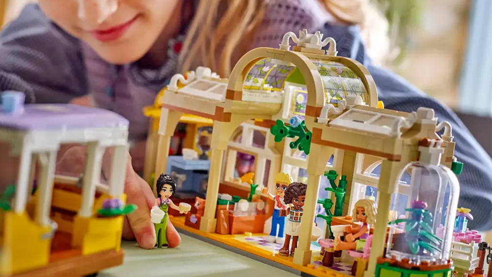 Dívka si hraje s minipanenkami a modelem květinářství a kavárny ze stavebnice LEGO® Friends_03