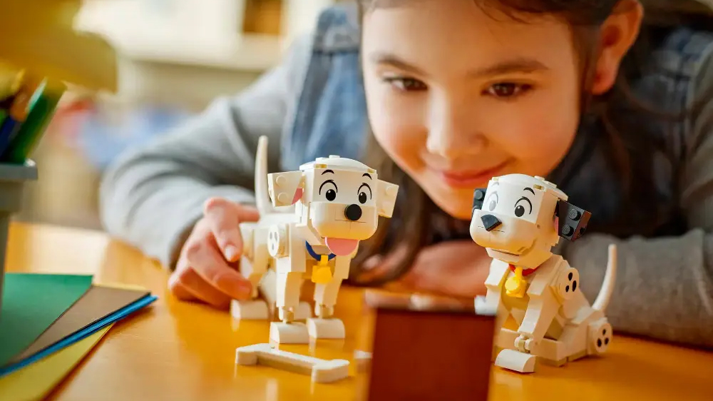 Holčička si hraje se &scaron;těň&aacute;tky dalmatinů ze stavebnice LEGO&reg; DISNEY, u kter&yacute;ch m&aacute; položenou kost z kostek a mini televizi_03