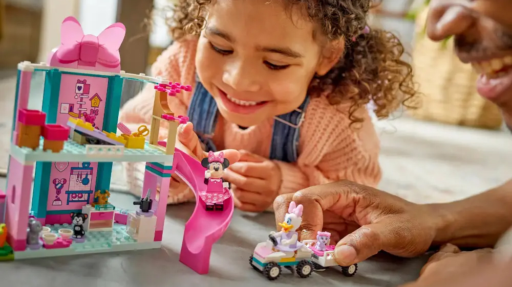 Otec s holčičkou si hrají se stavebnicí LEGO® Disney Minnie a hotel pro domácí mazlíčky, holčička posílá figurku dolů po skluzavce_03