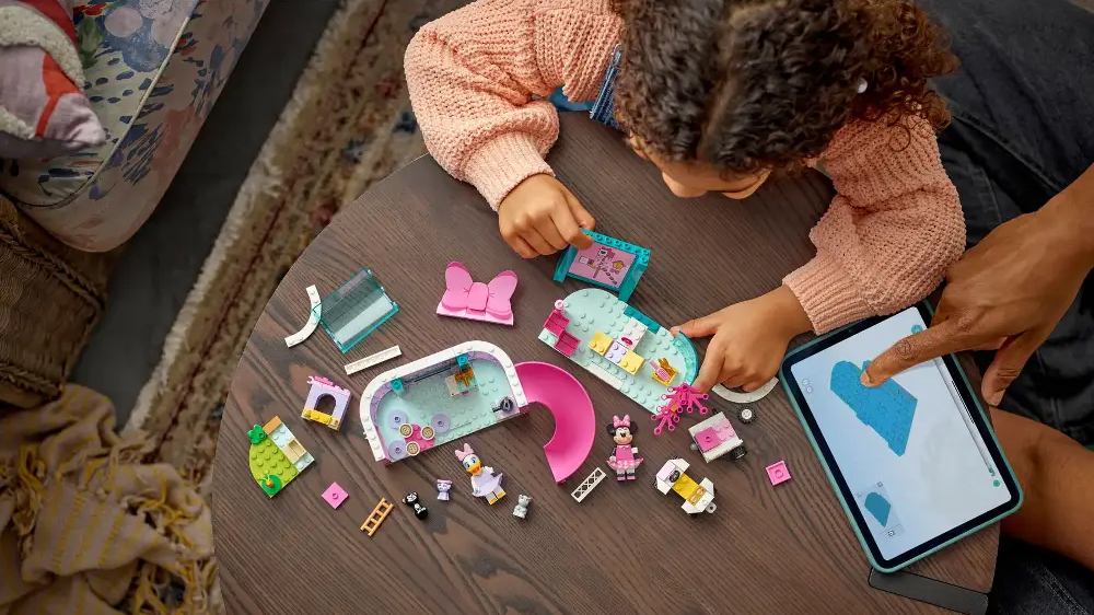 Holčička sestavuje stavebnici LEGO® Disney 43274 Minnie a hotel pro domácí mazlíčky a na tabletu má otevřenou aplikaci LEGO® Builder_04