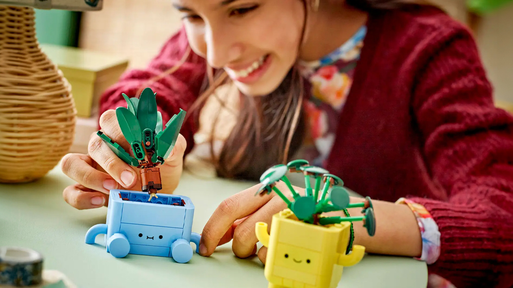 Mladá žena se usmívá při stavění stavebnice LEGO® Botanicals 10349 Veselé rostlinky_03