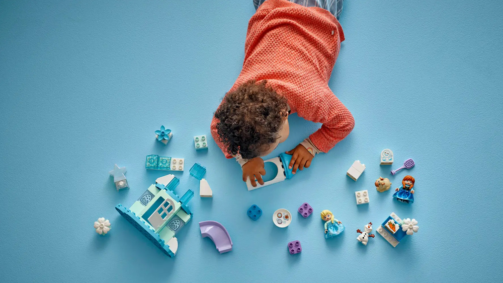 Holčička sestavuje stavebnici LEGO® DUPLO® Disney 10455 Ledové království: Anna a Elsa a oslava na hradě_02