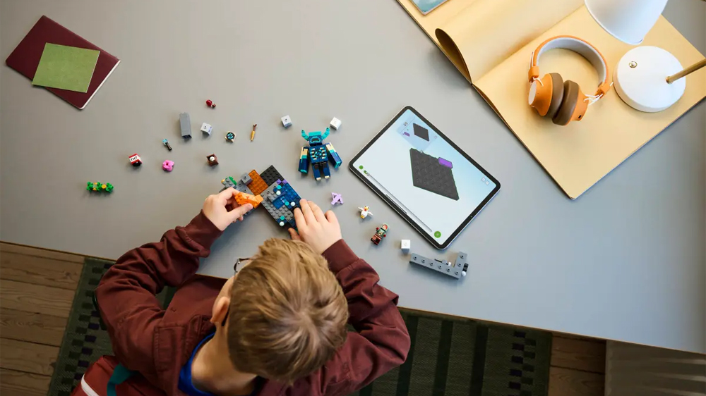 Chlapec staví stavebnici LEGO® Minecraft 21274 Setkání se Strážcem a má u toho návod v aplikaci LEGO® Builder v tabletu_04