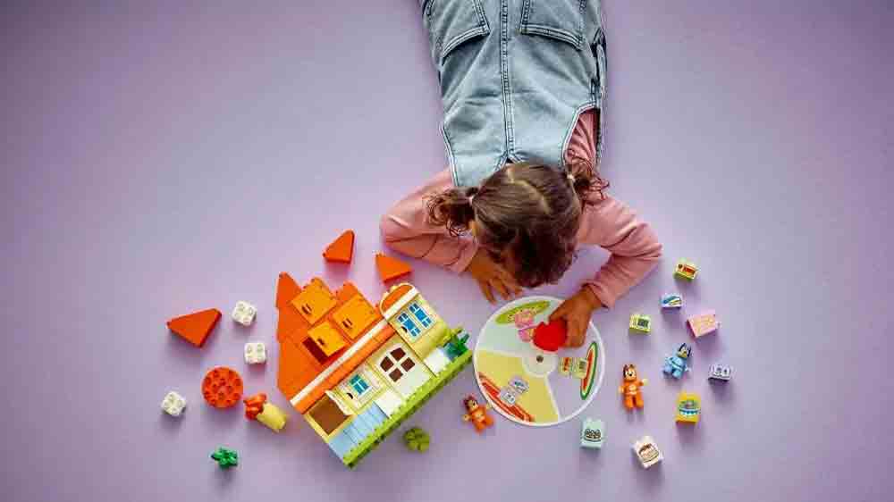 Holčička si hraje se stavebnicí LEGO® DUPLO® 10459 Dům Bluey a paměťová hra a roztáčí kolo z paměťové hry_03