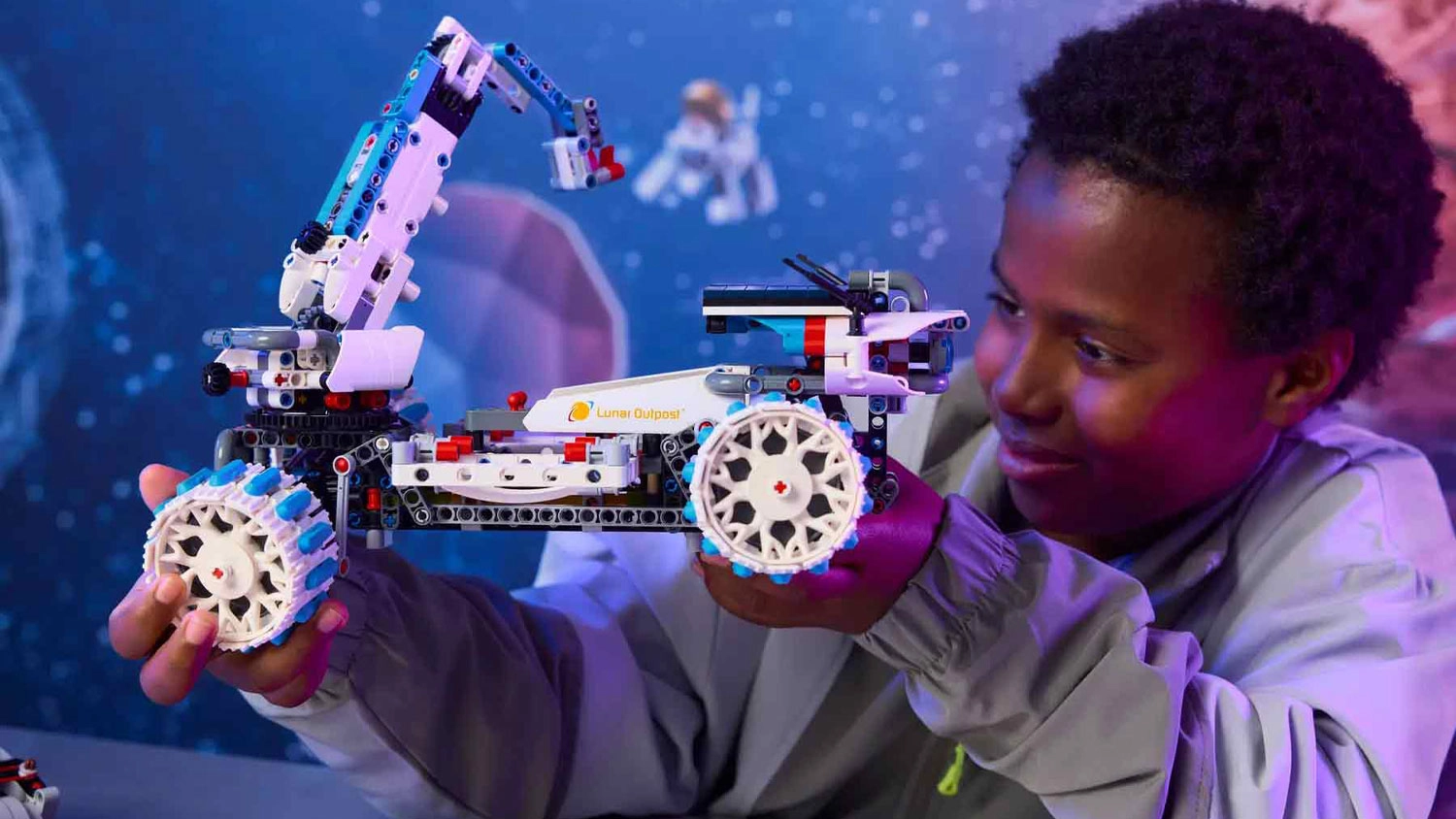 Chlapec drží v ruce lunární rover ze stavebnice LEGO® Technic 42211, který si s úsměvem prohlíží_02