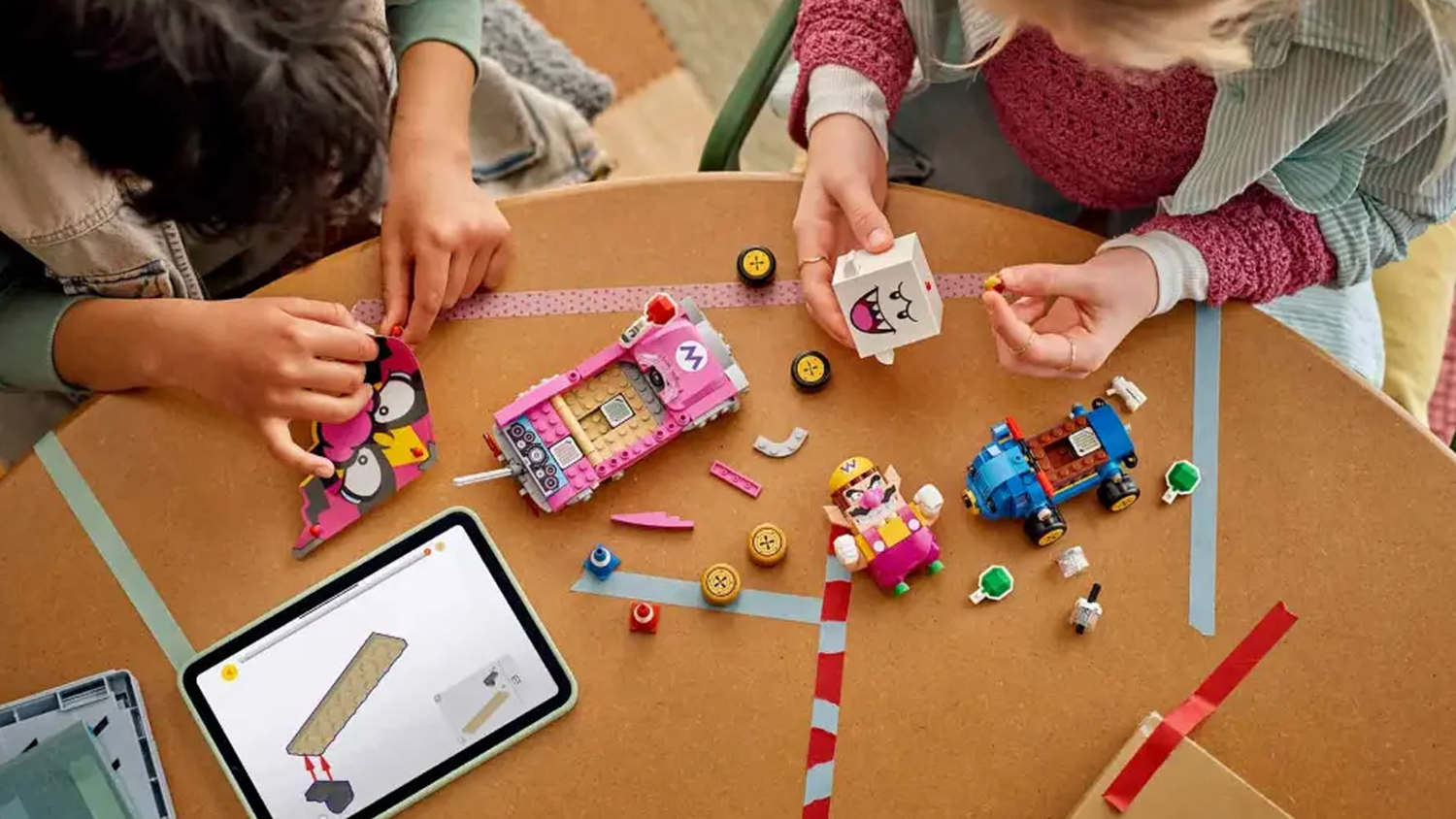 Chlapec s dievčaťom zostavuj&uacute; stavebnicu LEGO Super Mario 72038 Mario Kart &ndash; Wario a King Boo s pomocou aplik&aacute;cie v tablete_04