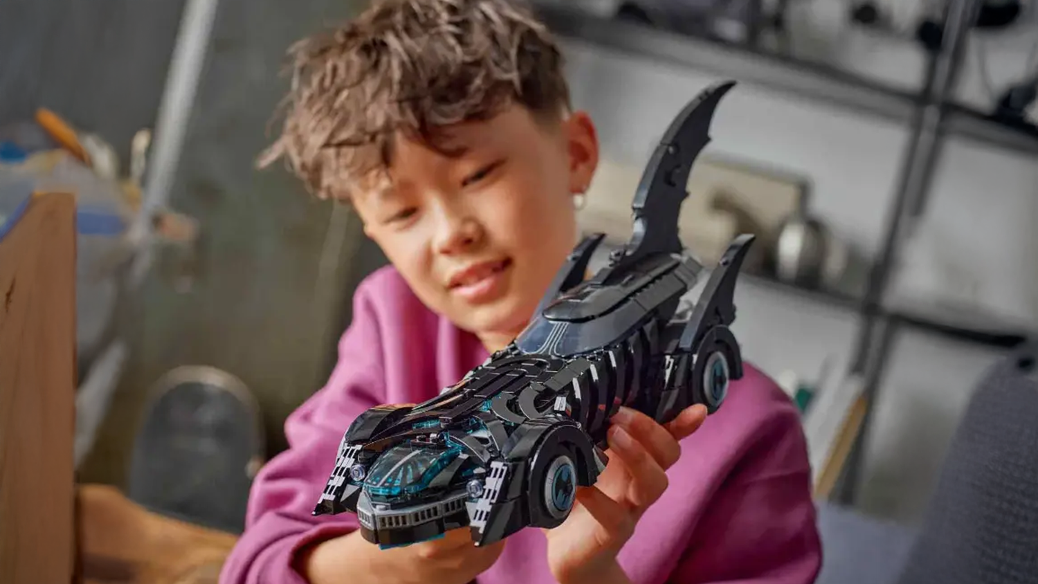 Chlapec obdivně pohl&iacute;ž&iacute; na Batmobil ze stavebnice LEGO&reg;, kter&yacute; drž&iacute; v rukou_03