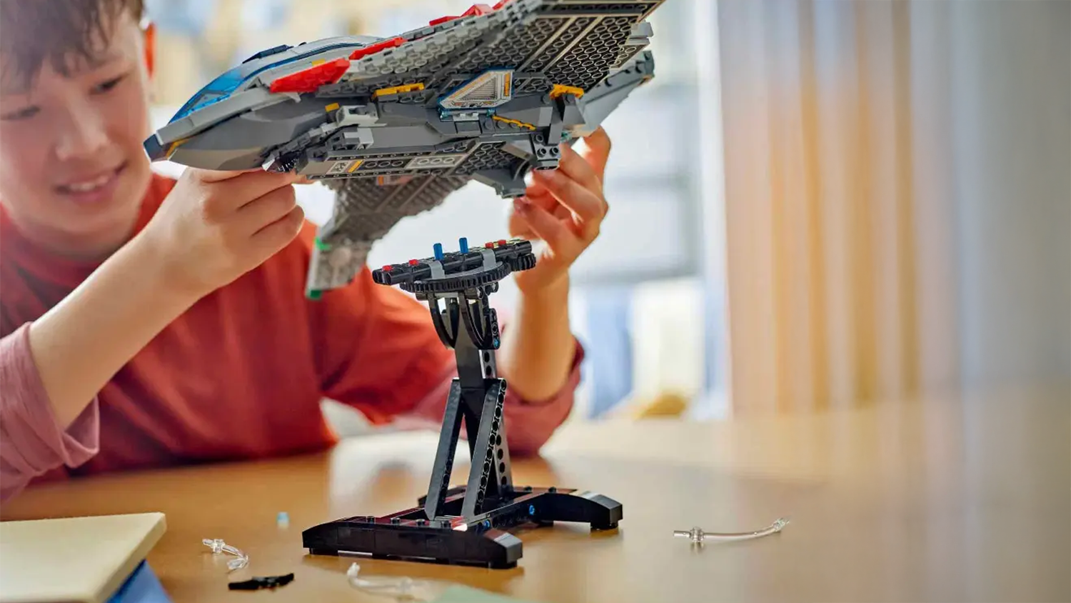 Usm&iacute;vaj&iacute;c&iacute; se chlapec odděluje model st&iacute;hačky Quinjet od stojanu_04