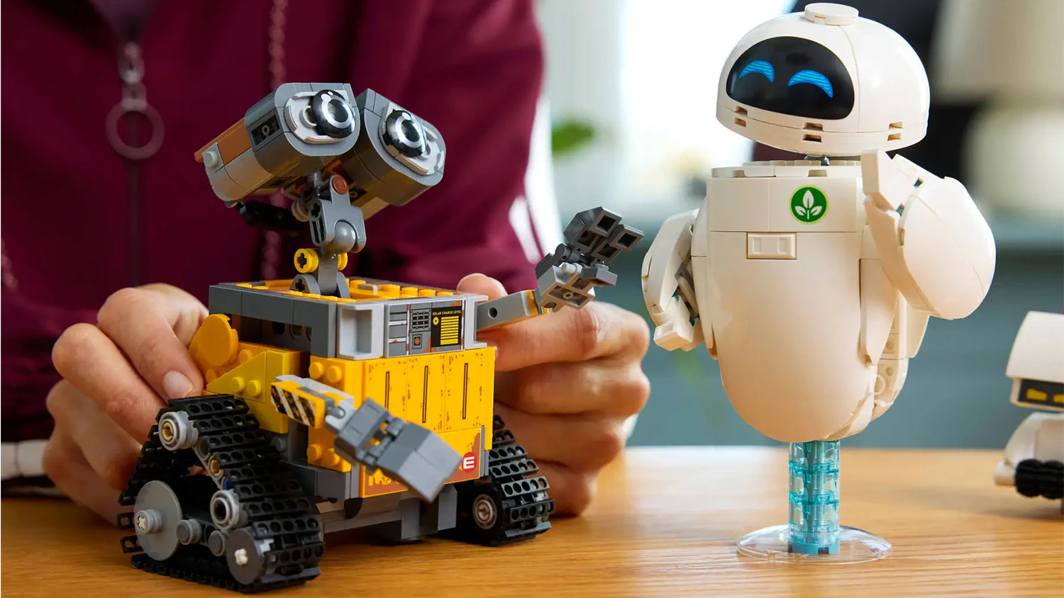 Žena polohuje figurku VALL&bull;Iho stoj&iacute;c&iacute; vedle figurky EVY ze stavebnice LEGO&reg;