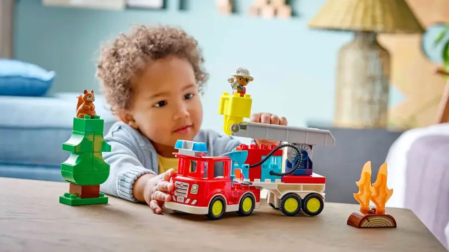 Malý chlapec si hraje s figurkou hasiče ve vozidle ze stavebnice LEGO® DUPLO® (10473).