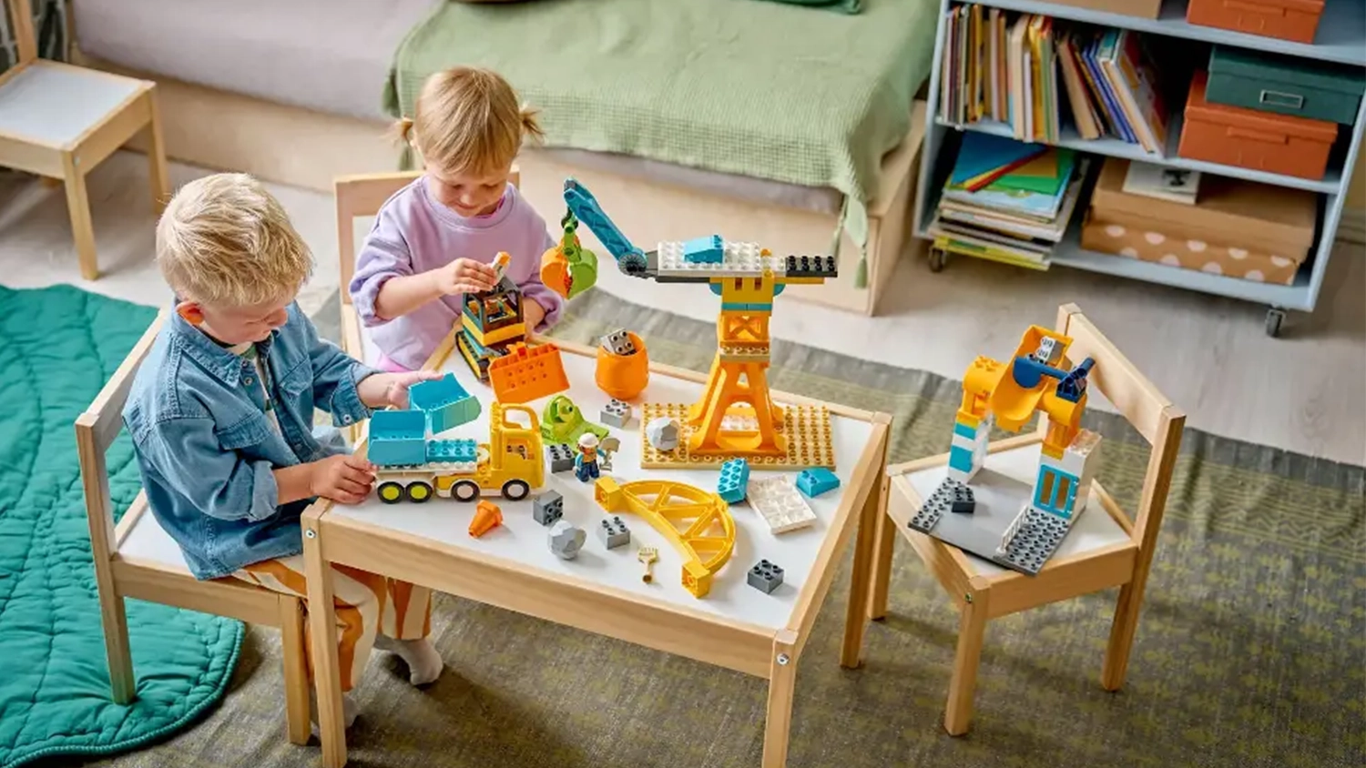 Chlapec s holčičkou sed&iacute; u stolku a hraj&iacute; si se stavebnic&iacute; LEGO&reg; DUPLO&reg; Město 10476 Staveni&scaron;tě a vozidla 3v1.