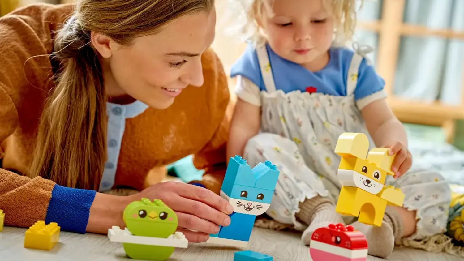 Usm&iacute;vaj&iacute;c&iacute; se žena s holčičkou si hraj&iacute; s figurkami zv&iacute;řat ze stavebnice LEGO&reg; DUPLO&reg; 10477 Roztomil&iacute; kreativn&iacute; mazl&iacute;čci 3v1.