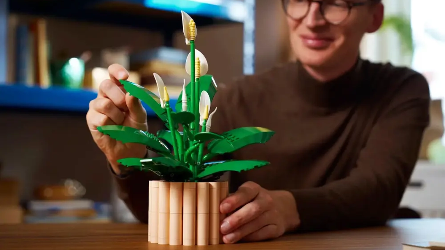 Usmívající se muž si prohlíží lopatkovec ze stavebnice LEGO® Botanicals (11504) a dotýká se listů.