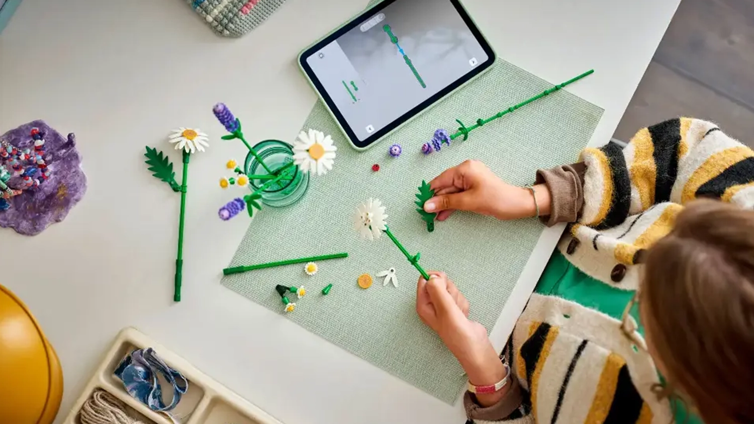 Dievča sklad&aacute; stavebnicu LEGO&reg; Botanicals 11508 Sedmokr&aacute;sky pomocou n&aacute;vodu v aplik&aacute;cii LEGO&reg; Builder.