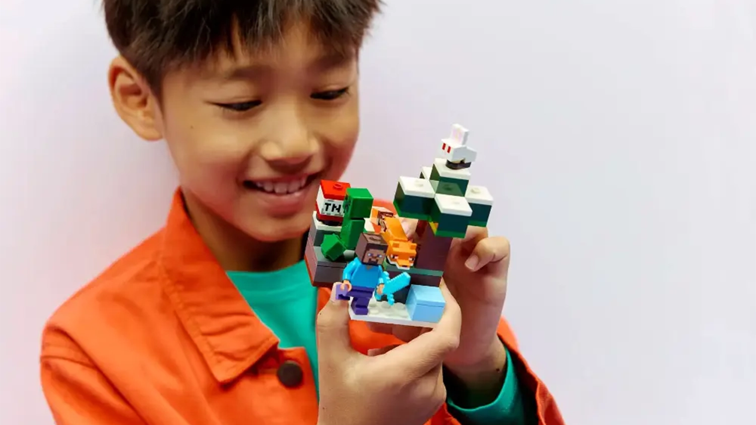 Usm&iacute;vaj&iacute;c&iacute; se chlapec si hraje se stavebnic&iacute; LEGO&reg; Minecraft&reg; 21583 Steve a dobrodružstv&iacute; v tajze.