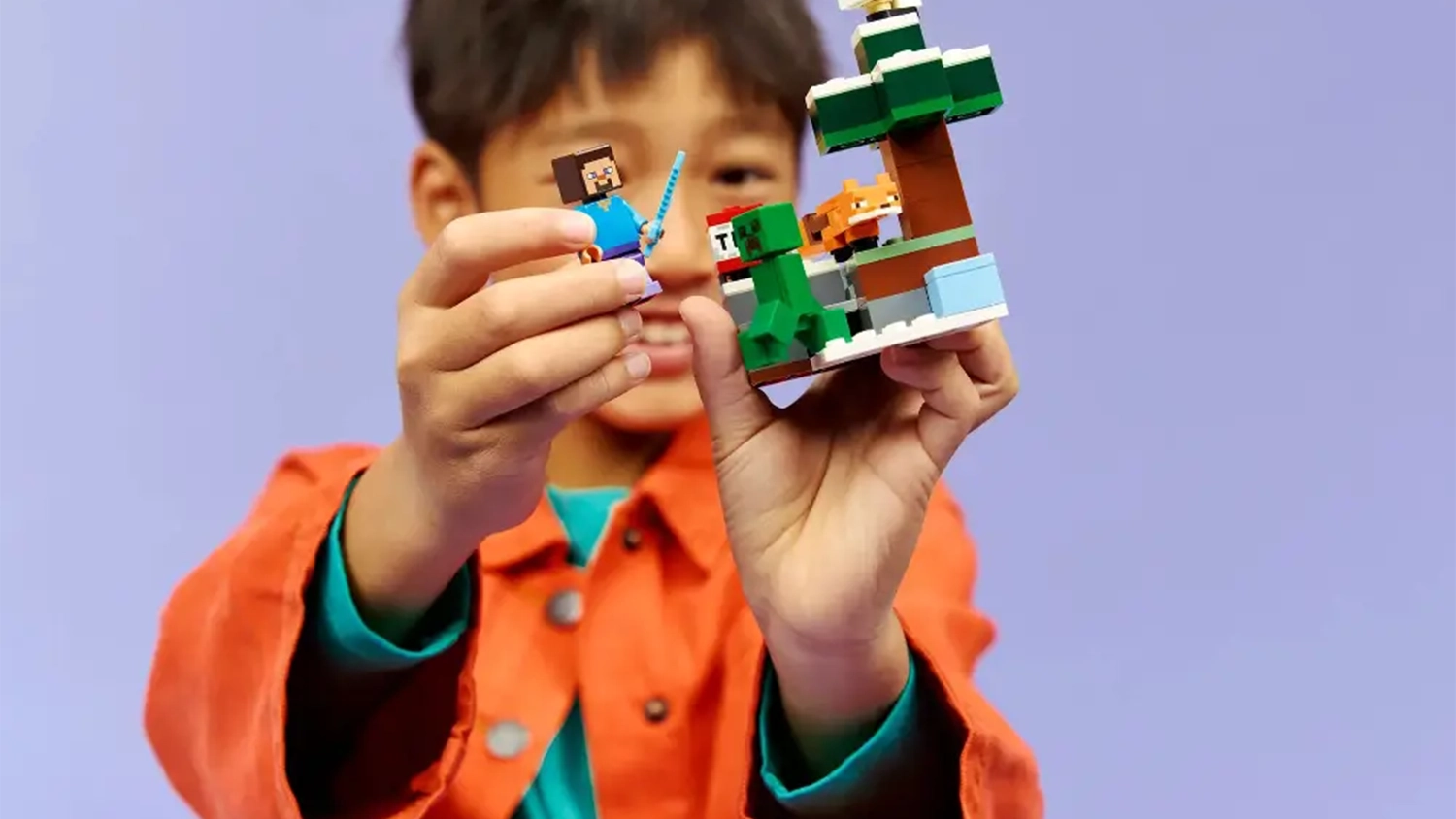 Usm&iacute;vaj&iacute;c&iacute; se chlapec drž&iacute; a obdivuje stavebnici LEGO&reg; Minecraft&reg; 21583 Steve a dobrodružstv&iacute; v tajze.
