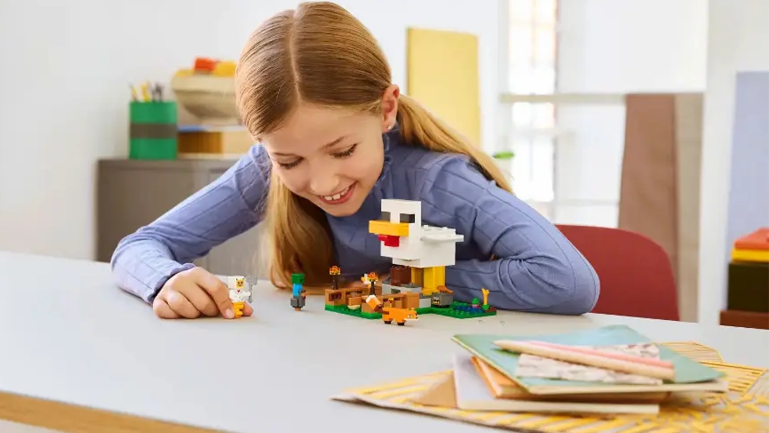 Usmívající se dívka si hraje se stavebnicí LEGO® Minecraft® 21585 Slepičí farma.