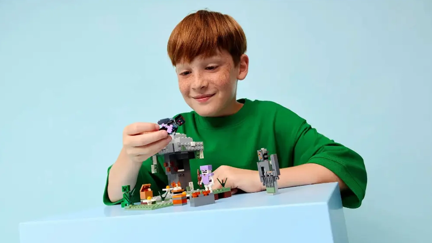 Usmievajúci sa chlapec sa hrá so stavebnicou LEGO® Minecraft® 21586 Bledá záhrada.