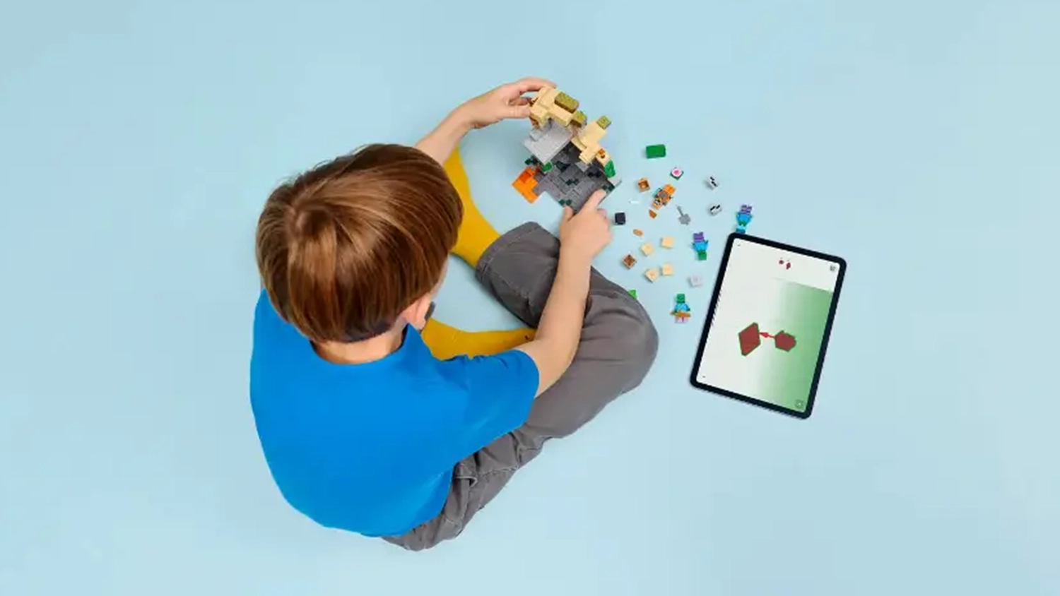Chlapec skl&aacute;d&aacute; stavebnici LEGO&reg; Minecraft&reg; 21587 Zombie kobka a na tabletu m&aacute; otevřen&yacute; n&aacute;vod v aplikaci LEGO&reg; Builder.