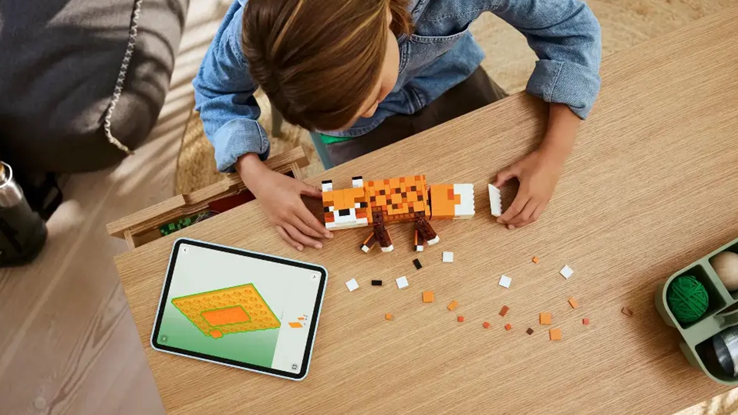 Dievča sklad&aacute; stavebnicu LEGO&reg; Minecraft&reg; 21588 L&iacute;&scaron;ka a m&aacute; otvoren&yacute; n&aacute;vod v aplik&aacute;cii LEGO&reg; Builder na tablete.