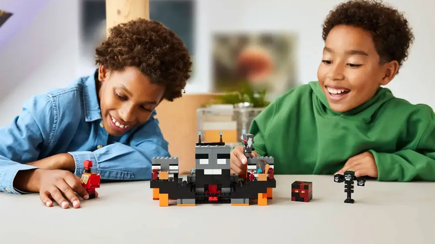 Dva smějící se chlapci si hrají se stavebnicí LEGO® Minecraft® 21590 Souboj s Witherem.