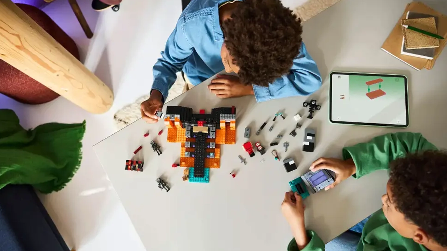Dva chlapci sestavují stavebnici LEGO® Minecraft® 21590 Souboj s Witherem a mají otevřený návod v aplikaci LEGO® Builder na tabletu.