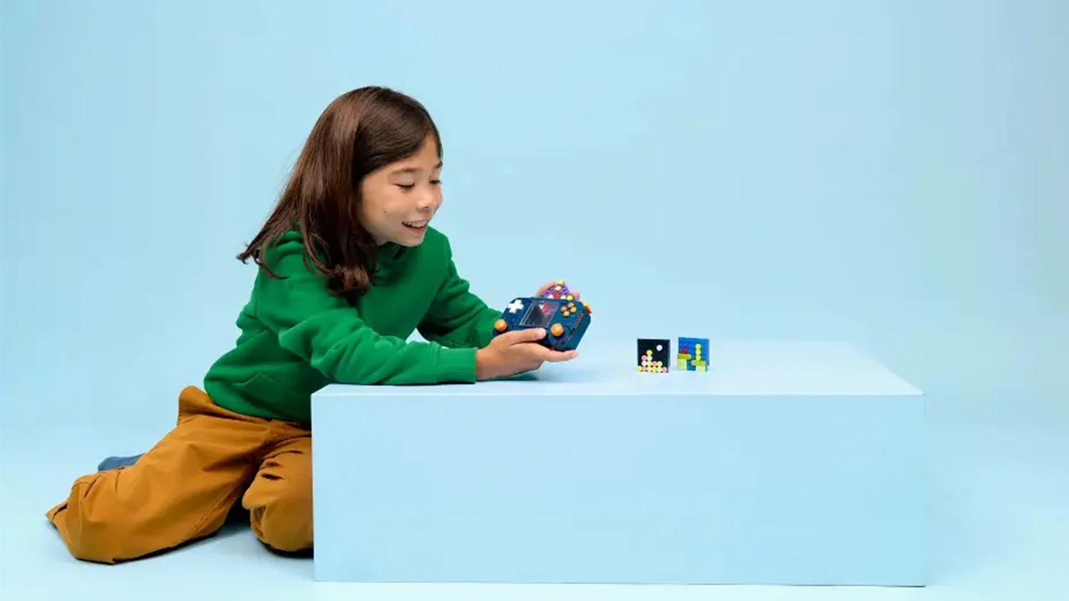 Dieťa s úsmevom vkladá kazety z kociek do modelu hernej konzoly zo stavebnice LEGO® Creator 3 v 1 31380.