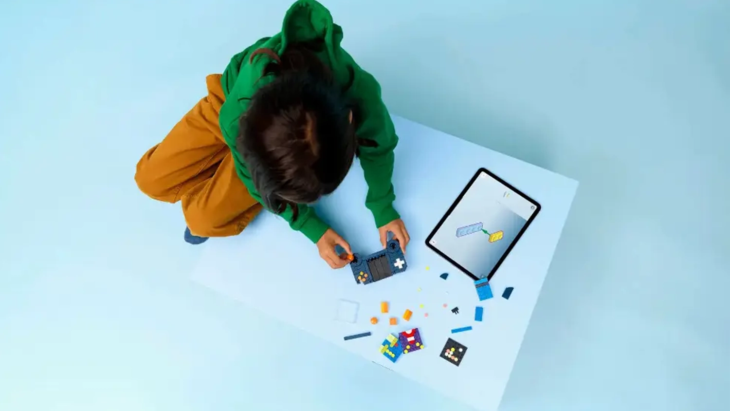 Dieťa skladá stavebnicu LEGO® Creator 3 v 1 31380 Retro herná konzola s pomocou návodu v aplikácii LEGO® Builder na tablete.