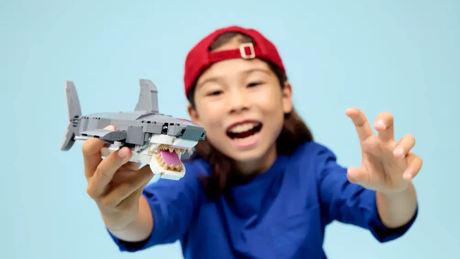 D&iacute;tě drž&iacute; v ruce model ze stavebnice LEGO&reg; Creator 3 v 1 31381 Divok&yacute; žralok a truhla s pokladem